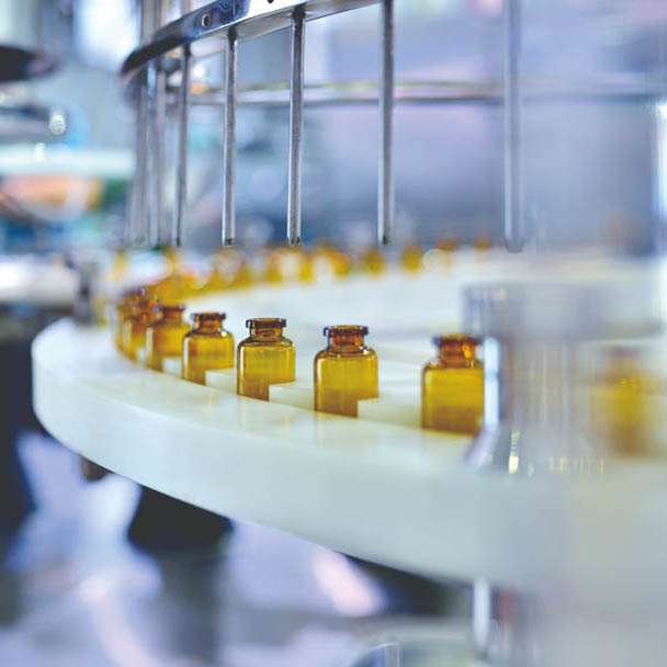 Close-up of brown glass bottle filling at production line